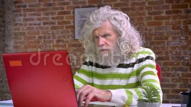 一位留着白长胡子和头发的<strong>老奶奶</strong>坐在砖房里专心致志地打着红电脑